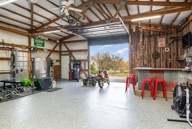 garage featuring stainless steel fridge, a workshop area, and a garage door opener