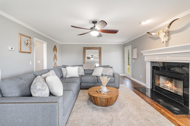 living room featuring wood-type flooring, ornamental molding, and a tiled fireplace