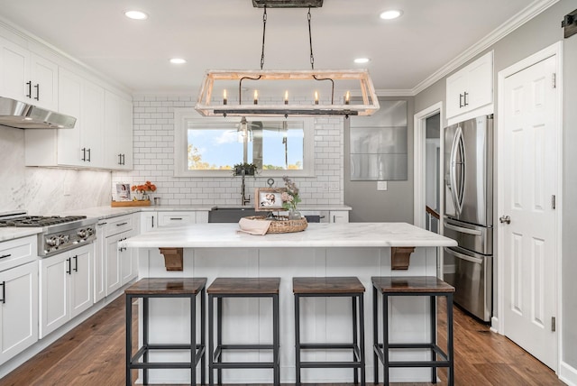 kitchen with a breakfast bar, ornamental molding, appliances with stainless steel finishes, a kitchen island, and white cabinetry