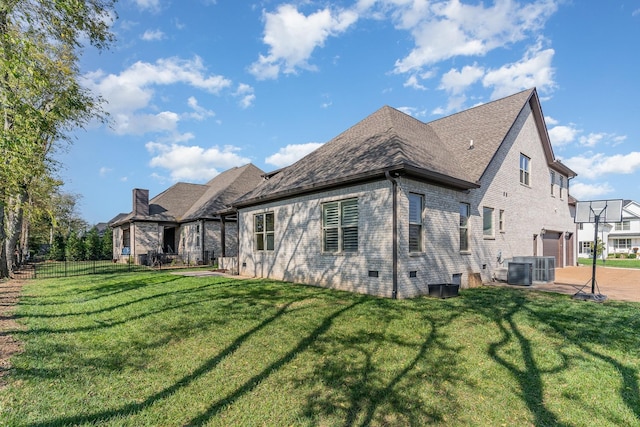 back of house featuring a lawn, cooling unit, and a garage