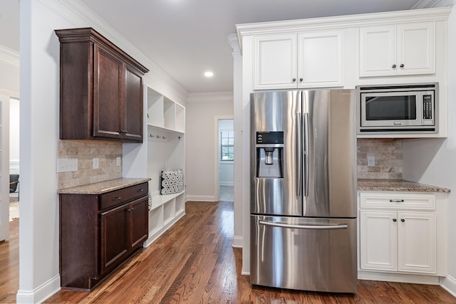 kitchen with light stone countertops, tasteful backsplash, crown molding, white cabinets, and appliances with stainless steel finishes