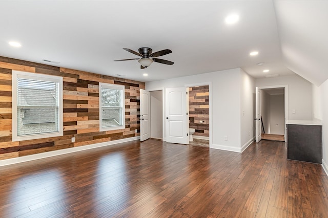 unfurnished living room featuring wood walls, ceiling fan, and dark wood-type flooring