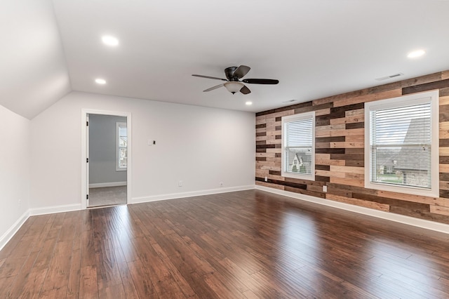 unfurnished living room featuring wooden walls, ceiling fan, dark hardwood / wood-style floors, and lofted ceiling