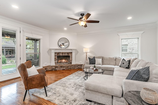 living room with hardwood / wood-style flooring, ceiling fan, crown molding, and a fireplace