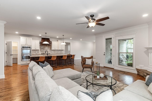 living room featuring dark hardwood / wood-style floors, ceiling fan, ornamental molding, and sink