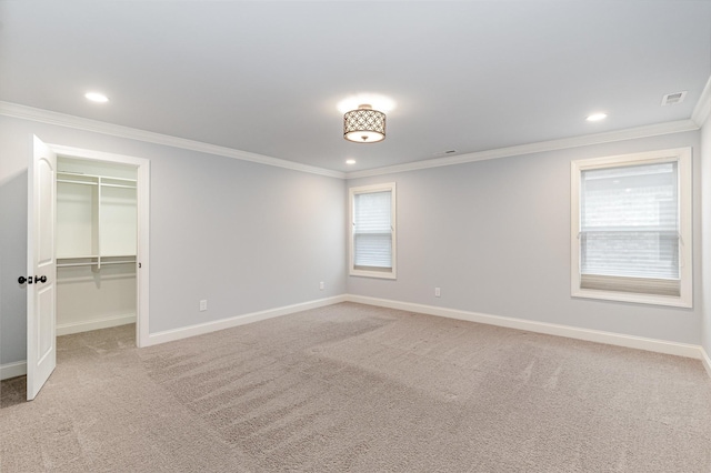 unfurnished bedroom with carpet flooring, a spacious closet, ornamental molding, and a closet