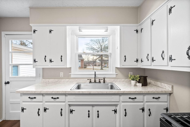 kitchen featuring white cabinetry, sink, and range