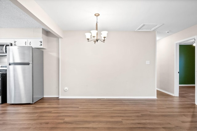 kitchen with appliances with stainless steel finishes, a chandelier, hardwood / wood-style floors, white cabinetry, and hanging light fixtures