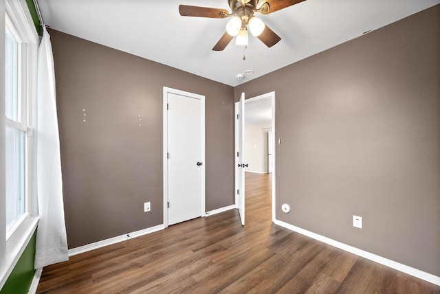 unfurnished bedroom with ceiling fan and dark hardwood / wood-style flooring