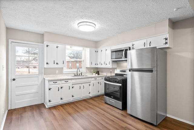 kitchen featuring white cabinets, stainless steel appliances, a wealth of natural light, and sink