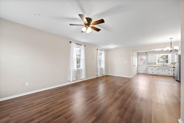 unfurnished living room featuring ceiling fan with notable chandelier, hardwood / wood-style flooring, and sink