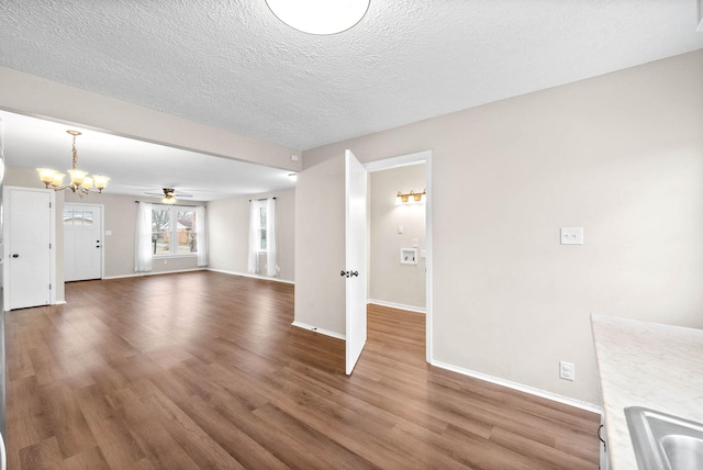 unfurnished living room with a textured ceiling, dark hardwood / wood-style flooring, ceiling fan with notable chandelier, and sink