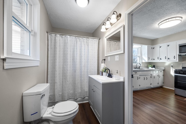 bathroom with hardwood / wood-style flooring, plenty of natural light, toilet, and a textured ceiling