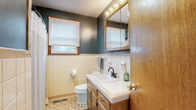 bathroom with vanity, toilet, a shower with shower curtain, and tile walls