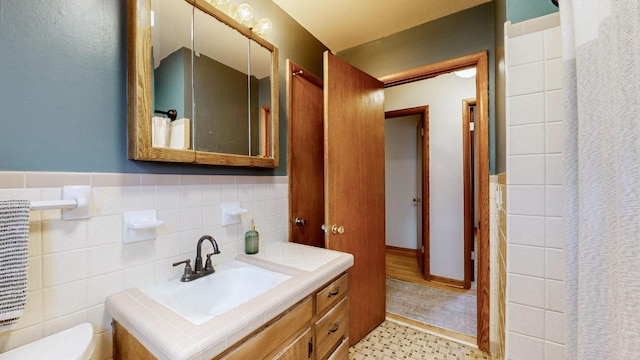 bathroom with tile walls, vanity, and toilet