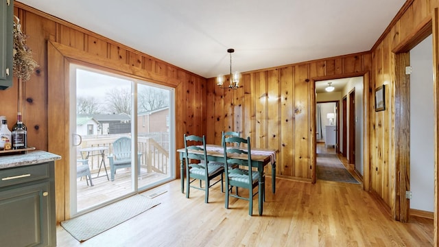 dining room featuring wood walls, light hardwood / wood-style flooring, and a notable chandelier