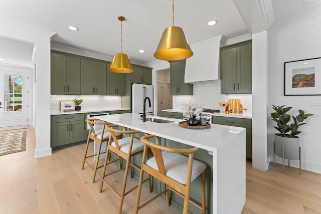 kitchen with sink, green cabinets, hanging light fixtures, appliances with stainless steel finishes, and ornamental molding