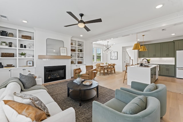 living room with a fireplace, sink, ornamental molding, and light hardwood / wood-style floors