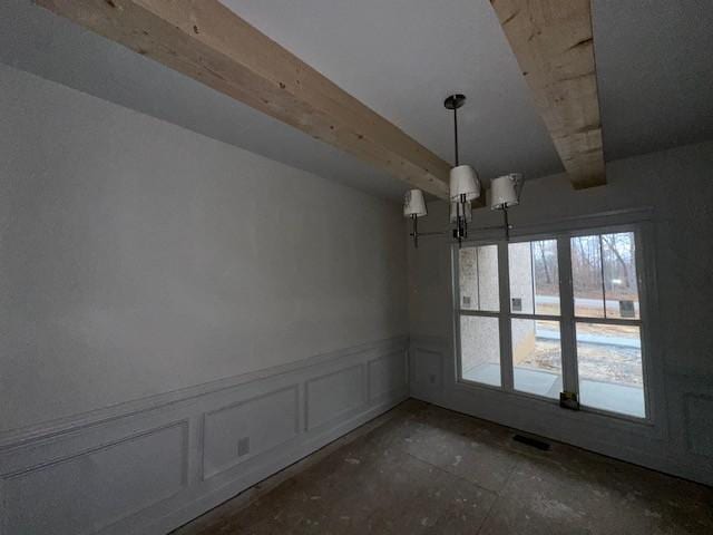 unfurnished dining area featuring a notable chandelier, a decorative wall, beamed ceiling, and wainscoting