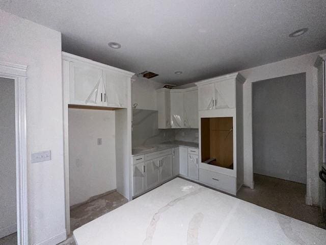 kitchen featuring concrete flooring and white cabinetry