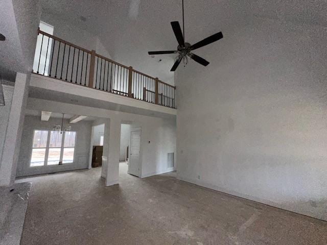 unfurnished living room with visible vents, a towering ceiling, a ceiling fan, a textured ceiling, and concrete floors