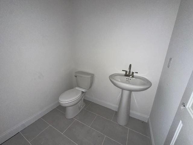 bathroom featuring tile patterned flooring, baseboards, and toilet