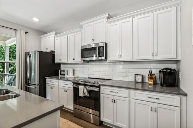 kitchen with tasteful backsplash, dark hardwood / wood-style flooring, white cabinets, and appliances with stainless steel finishes