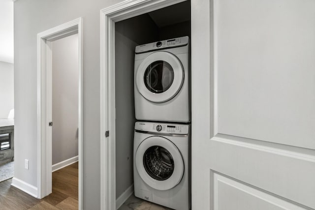 laundry room with stacked washer and dryer and hardwood / wood-style floors