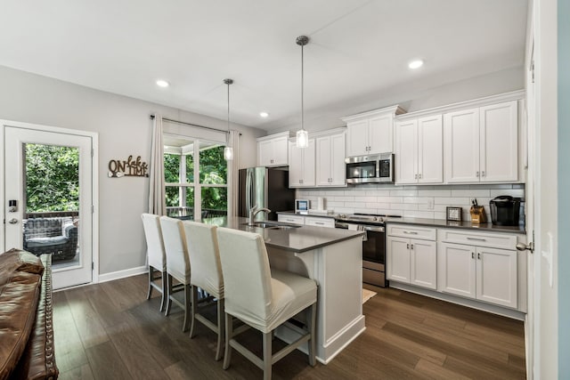 kitchen featuring decorative backsplash, white cabinets, stainless steel appliances, and decorative light fixtures