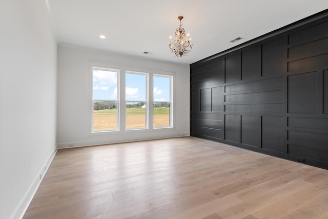 spare room featuring light hardwood / wood-style flooring, a chandelier, and ornamental molding