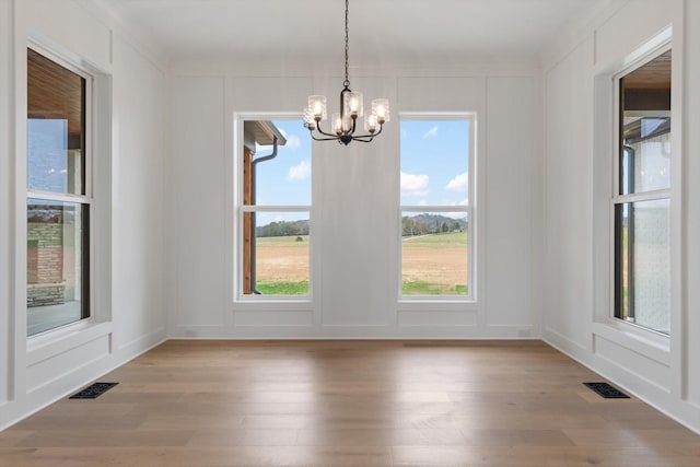 unfurnished dining area featuring light hardwood / wood-style floors and a notable chandelier