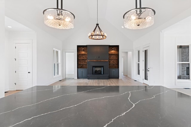 unfurnished living room with an inviting chandelier, a fireplace, and vaulted ceiling