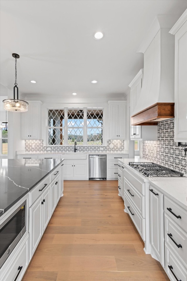 kitchen featuring premium range hood, pendant lighting, white cabinets, and stainless steel appliances