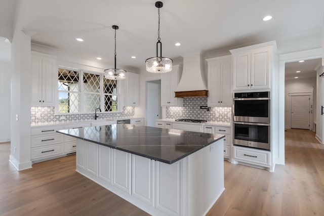 kitchen featuring a kitchen island, white cabinetry, premium range hood, and stainless steel appliances