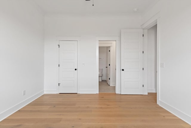 unfurnished bedroom featuring ensuite bath, crown molding, and light hardwood / wood-style flooring