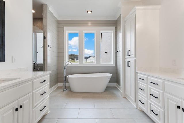 bathroom with tile patterned floors, a bathtub, vanity, and ornamental molding