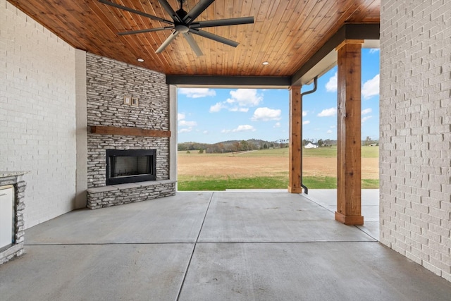 view of patio with ceiling fan, a large fireplace, and a rural view