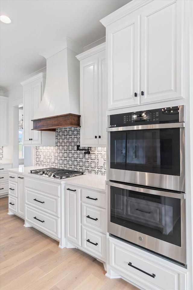 kitchen featuring white cabinetry, appliances with stainless steel finishes, and custom exhaust hood