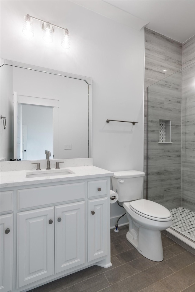 bathroom featuring tile patterned floors, toilet, vanity, and walk in shower