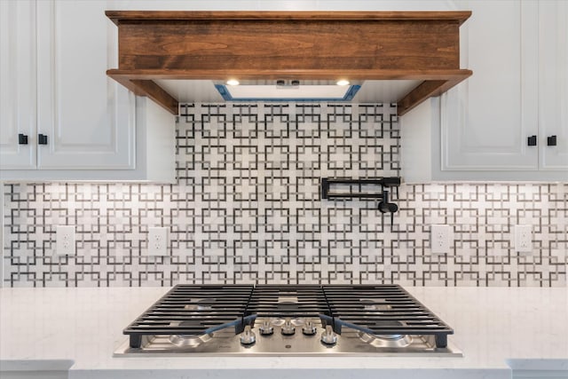 kitchen featuring custom range hood, tasteful backsplash, white cabinetry, and stainless steel gas stovetop