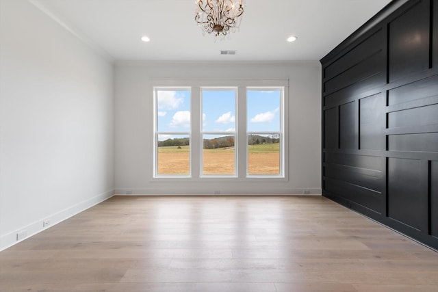 empty room featuring crown molding, light hardwood / wood-style flooring, and a chandelier