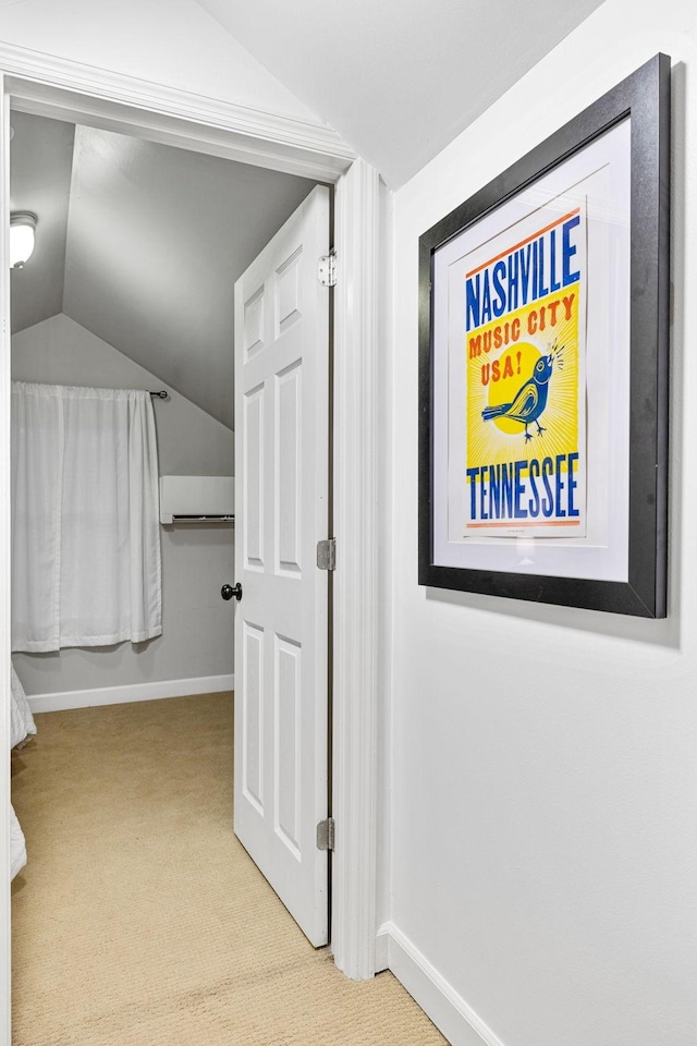 hall featuring an AC wall unit, light colored carpet, and lofted ceiling