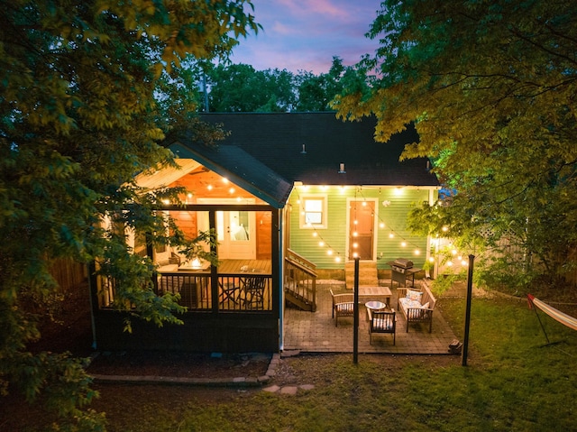 back house at dusk featuring a patio and an outdoor hangout area