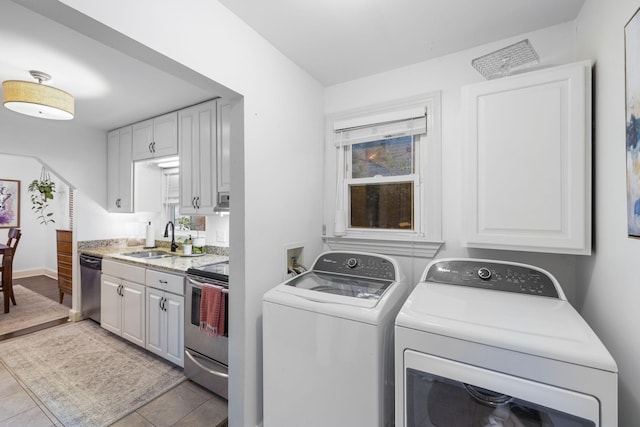 laundry room featuring washer and clothes dryer, light tile patterned floors, and sink