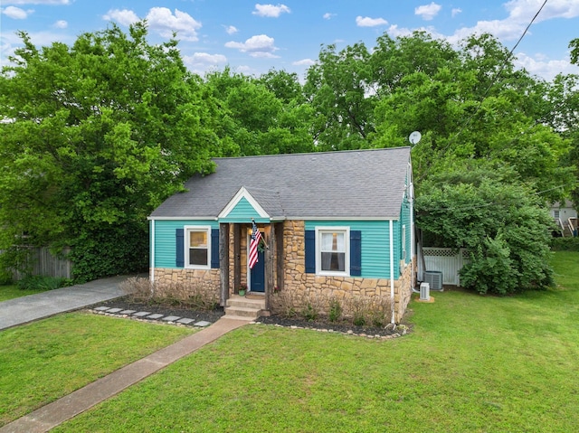 view of front of house with central AC and a front lawn