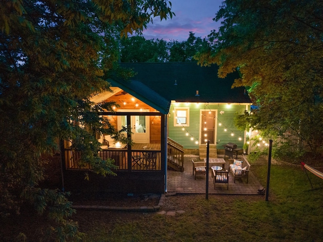 back house at dusk with an outdoor living space and a patio