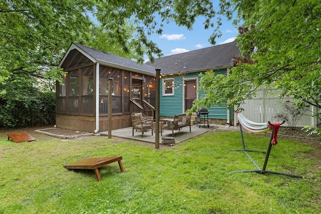 rear view of property with a yard, a patio area, and a sunroom