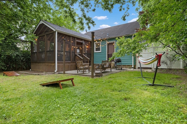 back of house featuring a lawn, a sunroom, and a patio