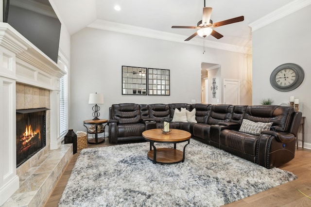 living room with ornamental molding, vaulted ceiling, ceiling fan, a fireplace, and light hardwood / wood-style floors