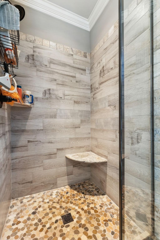 bathroom with a tile shower and crown molding